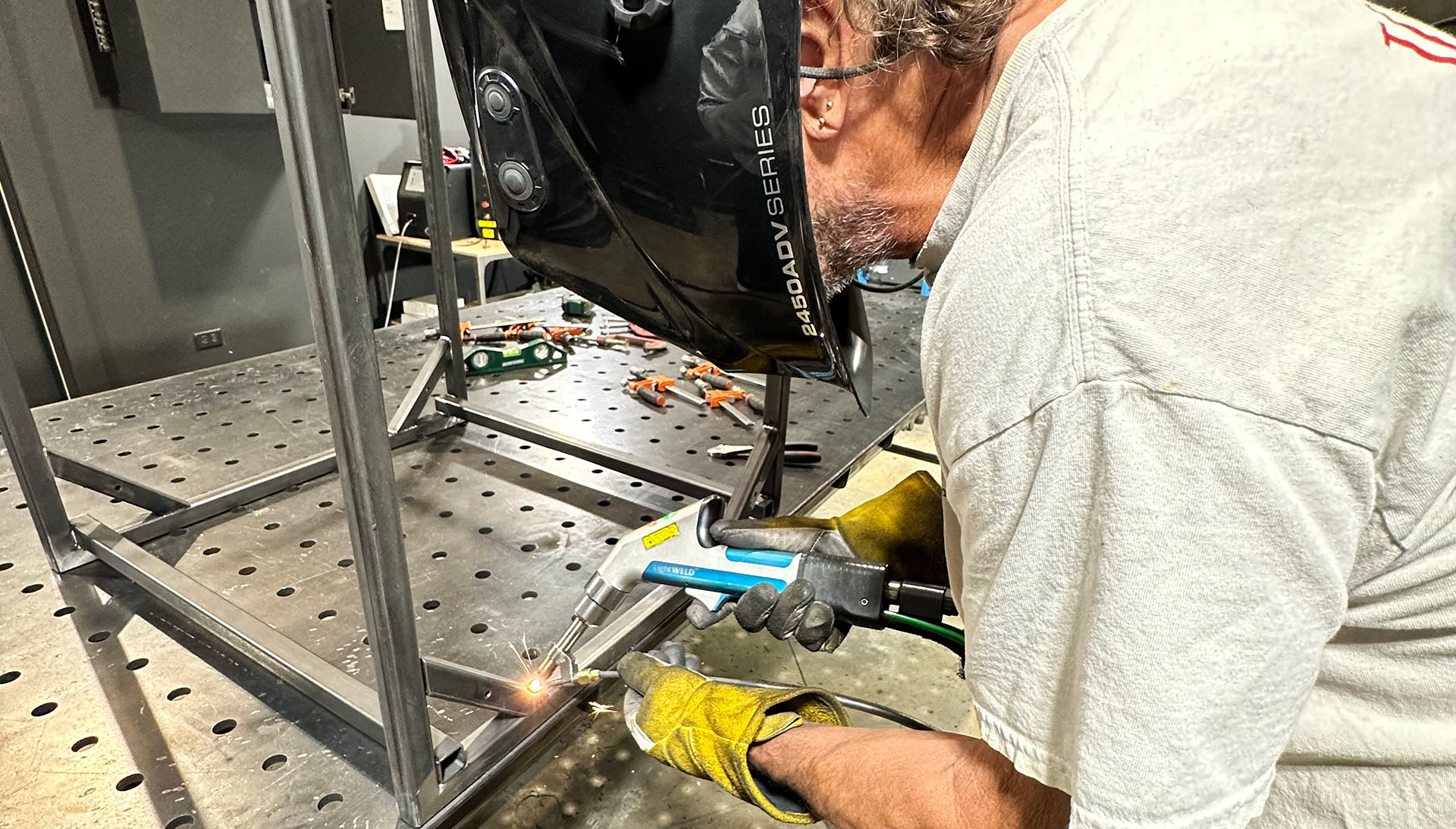 A welder using a laser welding torch to build a metal frame